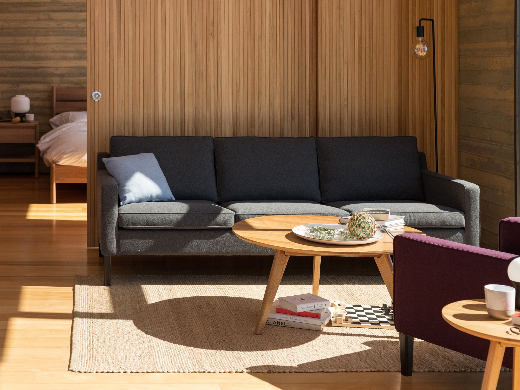 Dark grey couch in front of wood panel divider in mid century modern home